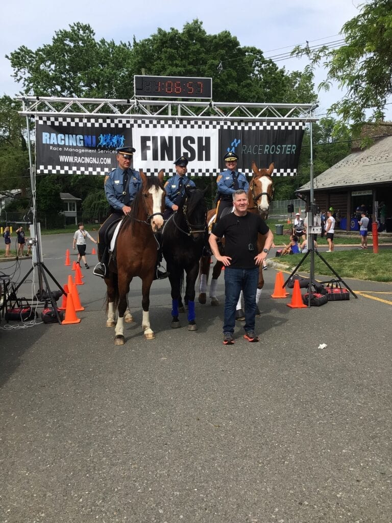 Two people with horses at a finish line outdoors.