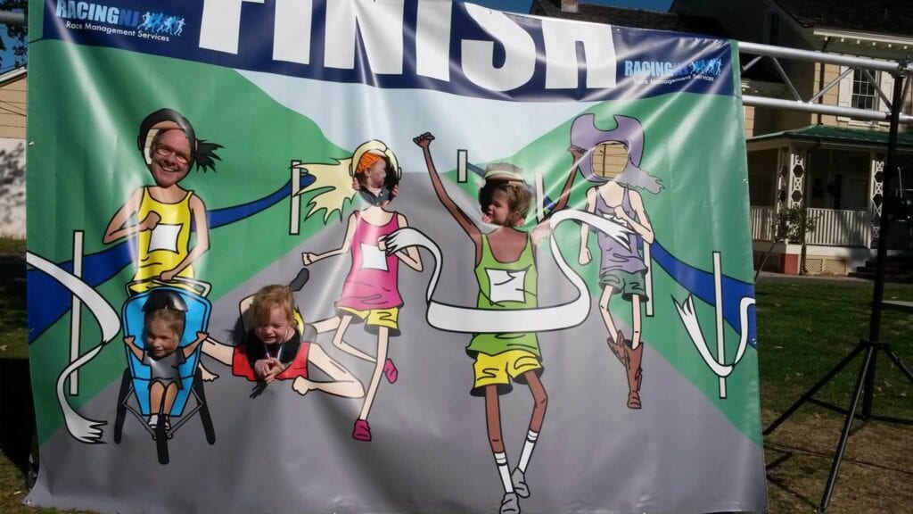 Cartoon runners celebrating at a finish line on a banner.
