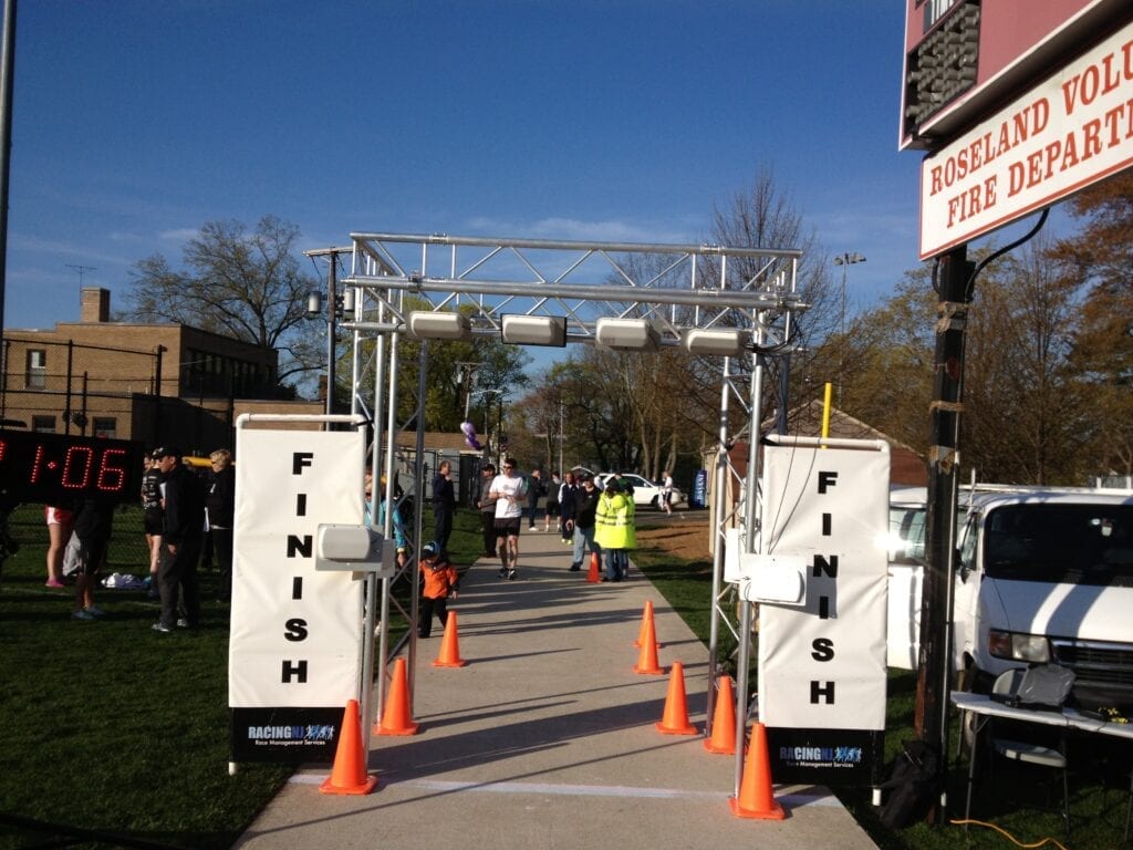 Runners passing through a race finish line on a sunny day.