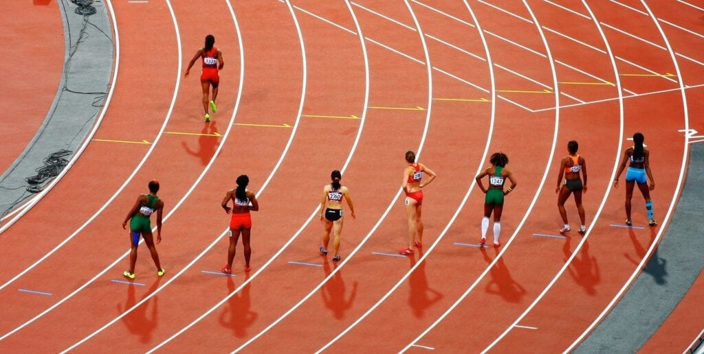 Five athletes preparing to start a race on a wet track.