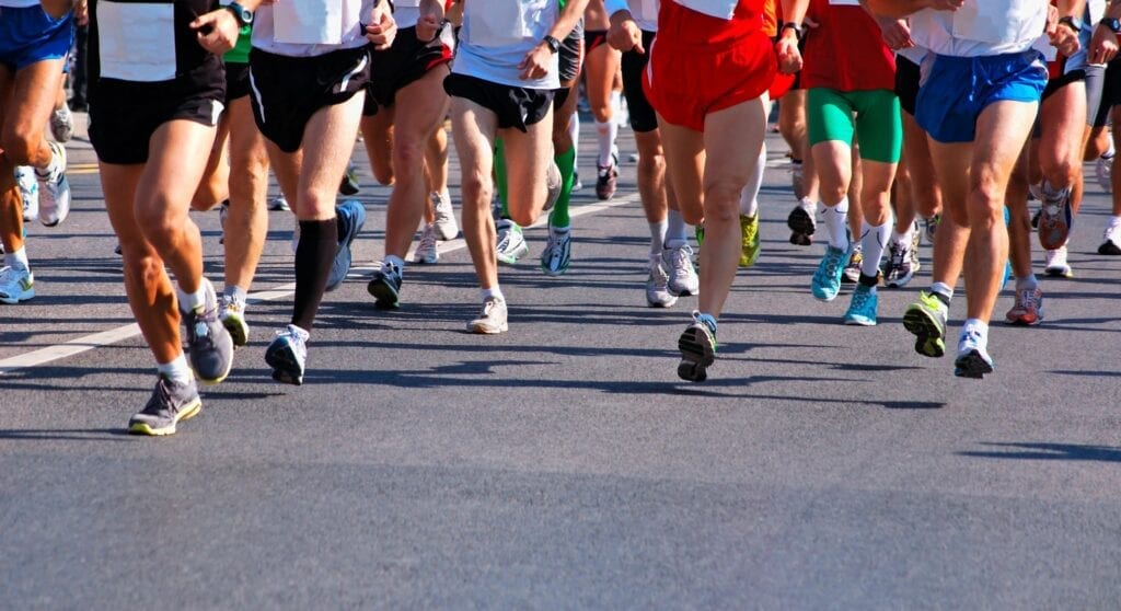 Runners' legs in a road race, showing movement and athletic wear.
